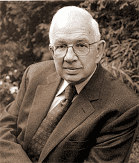 A man in suit and tie sitting outside.