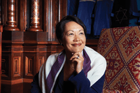 A woman sitting in front of a chair with her hand under chin.